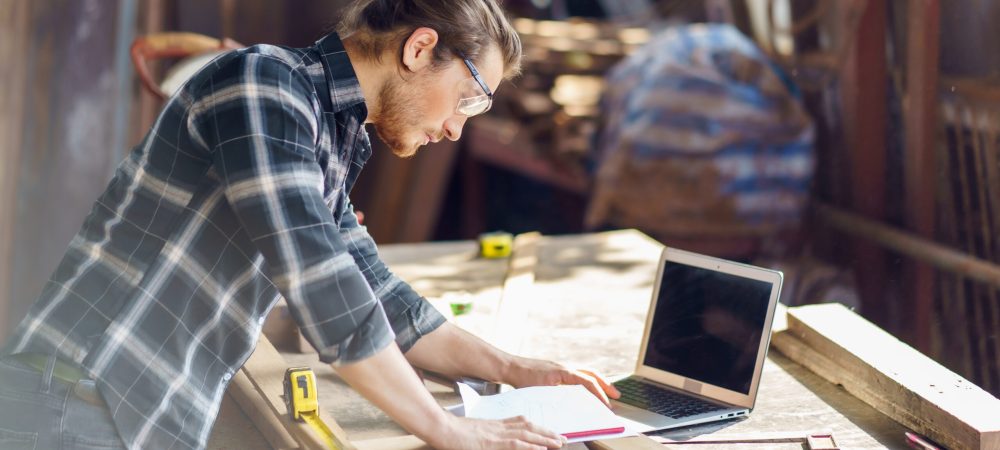 Young,Hipster,Carpenter,Man,Working,With,Computer,Laptop,In,Workshop